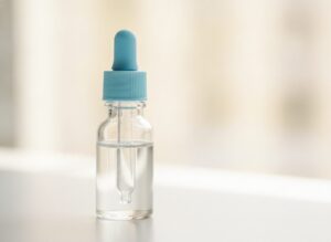 Флакон с каплями для носа и пипетка на фоне детской кроватки